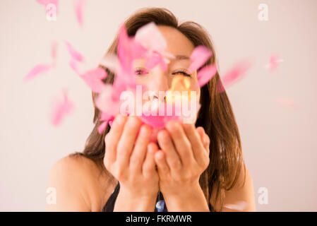 Mixed Race woman blowing confetti Banque D'Images