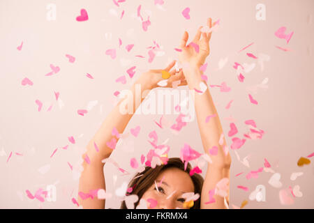 Mixed Race woman playing in confetti Banque D'Images