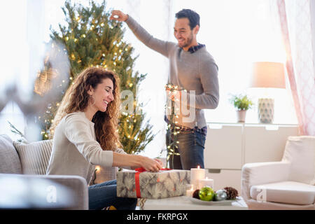 Couple decorating pour Noël dans la salle de séjour Banque D'Images
