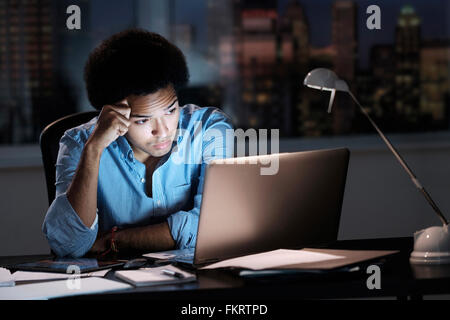 Mixed Race businessman travaillant tard in office Banque D'Images