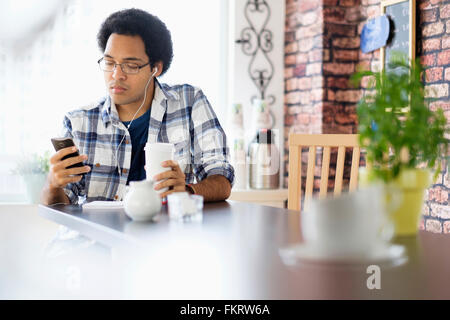 Mixed Race man using cell phone in coffee shop Banque D'Images