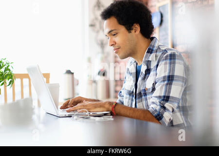 Mixed Race man using laptop in coffee shop Banque D'Images