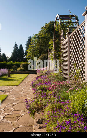 Pavage, bordure colorée des plantes, et l'écran de passage trellis - conçu, aménagé, le jardin d'été ensoleillé, Burley-en-Wharfedale, Yorkshire, Angleterre. Banque D'Images