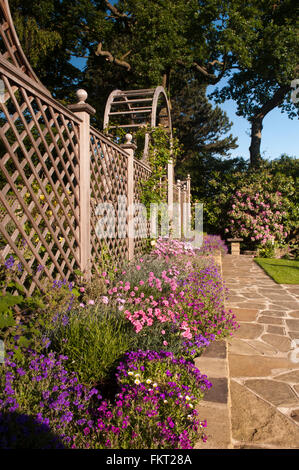 Pavage, bordure colorée des plantes, et l'écran de passage trellis - conçu, aménagé, le jardin d'été ensoleillé, Burley-en-Wharfedale, Yorkshire, Angleterre. Banque D'Images