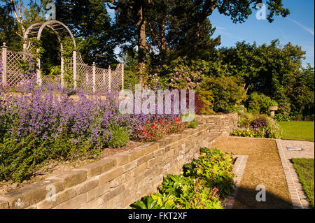 Cultures en terrasses, des plantes colorées, mur de pierre, trellis arch sous un ciel bleu - Conçu, aménagé, le jardin ensoleillé, Burley-en-Wharfedale, Yorkshire, Angleterre. Banque D'Images
