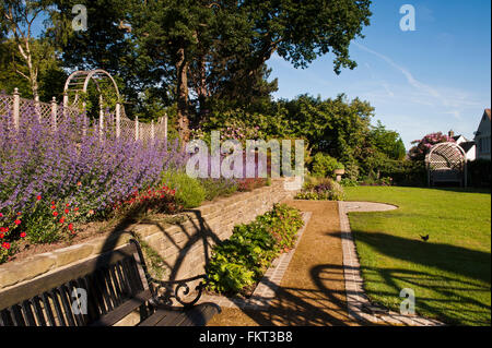 Beau jardin, traditionnel, conçu et aménagé avec terrasse & frontière coloré en été, sun - Burley-en-Wharfedale, West Yorkshire, Angleterre. Banque D'Images