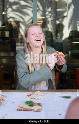 Caucasian girl eating pizza in cafe Banque D'Images