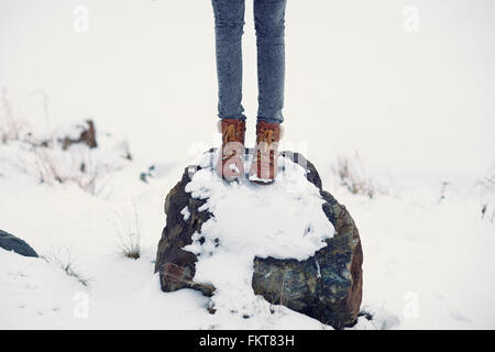 Caucasian teenage Girl standing on snowy rock Banque D'Images