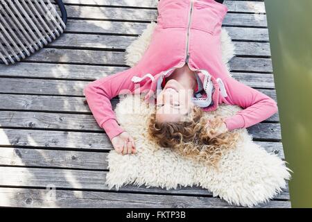 Jeune femme couchée sur un tapis à poils sur platelage, high angle Banque D'Images