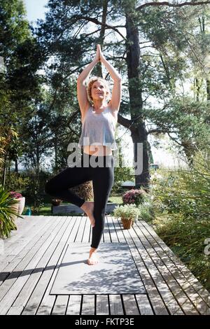Jeune femme faisant posture de l'arbre dans le jardin Banque D'Images