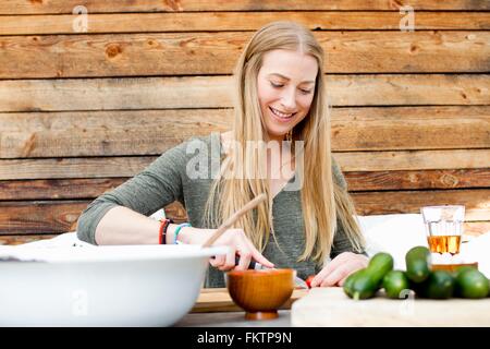 Mid adult woman preparing food at table outdoors Banque D'Images