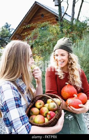 Deux amis transportant des produits cultivés sur place, une femme eating apple Banque D'Images