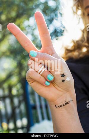 Woman making peace sign with hand Banque D'Images