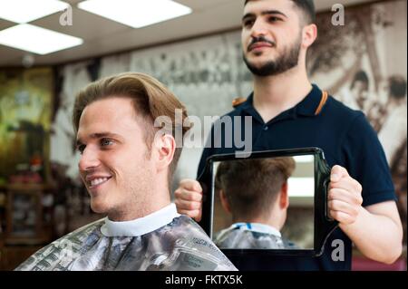 Salon de coiffure à l'aide d'un miroir pour montrer smiling customer coupe Banque D'Images