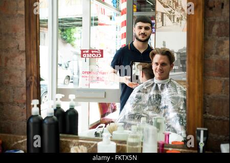 Image miroir de salon de coiffure à l'aide d'un miroir pour montrer smiling customer coupe Banque D'Images