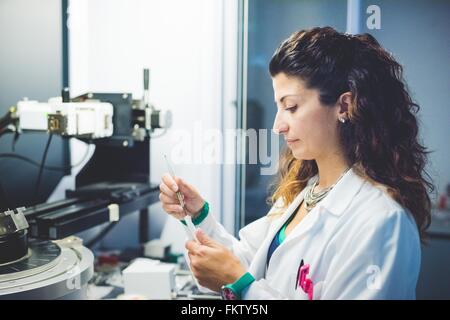 Female scientist la préparation de l'échantillon à film mince à la mesure à l'aide d'un diffractomètre de rayons x Banque D'Images