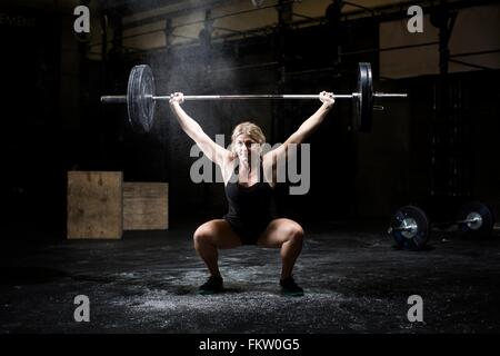 Jeune femme d'haltères haltérophilie sport foncé Banque D'Images