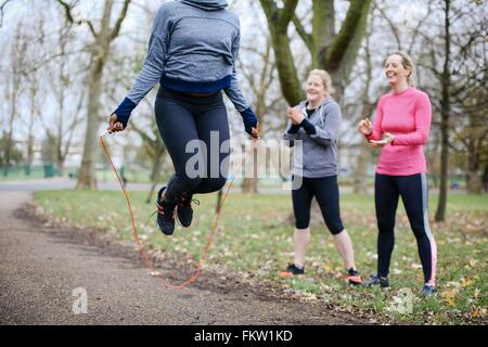 Portrait de jeune femme et les amis de la formation avec la corde à sauter dans le parc Banque D'Images