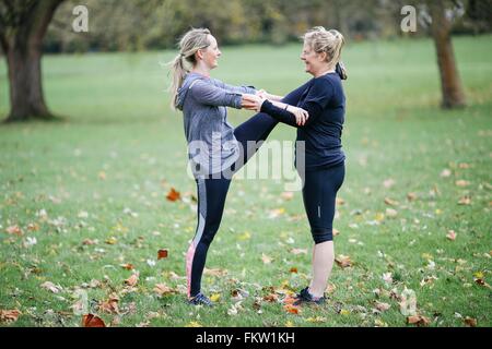 Deux femmes de faire des exercices d'échauffement avec les autres de Park Banque D'Images