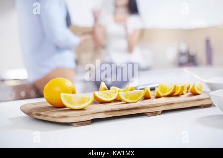 Les oranges en quartiers sur comptoir de la cuisine en face jeune couple Banque D'Images