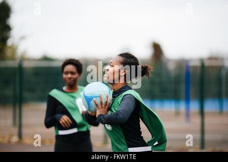 Les jeunes femelles adultes de netball joueur à jouer sur la cour de netball