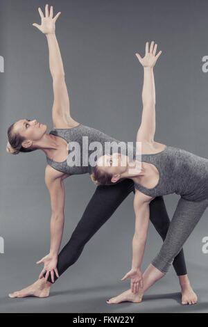 Les jeunes femmes pratiquant le yoga, fond gris Banque D'Images