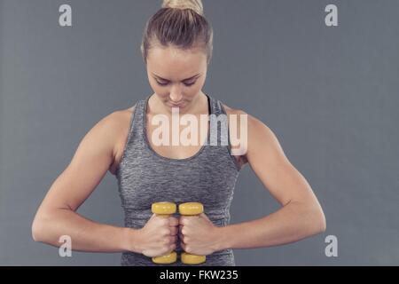 Young woman working out with dumbbells, fond gris Banque D'Images