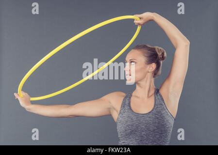 Jeune femme pratiquant avec hula hoop, fond gris Banque D'Images