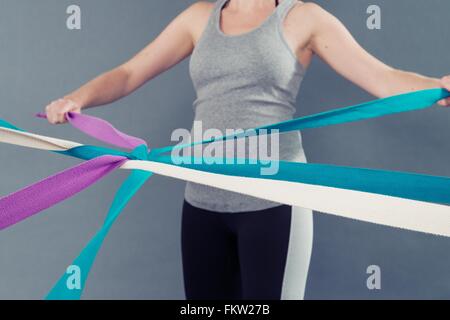 Jeune femme à l'aide de bagues de couleurs, fond gris Banque D'Images