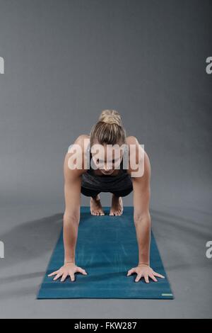 Jeune femme faisant de l'exercice de planches, fond gris Banque D'Images