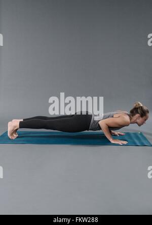 Jeune femme faisant de l'exercice de planches, fond gris Banque D'Images