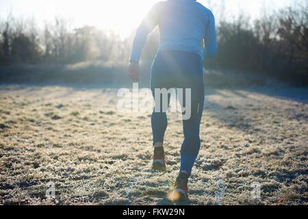 Vue arrière du coureur d'exécution sur l'herbe givrée Banque D'Images