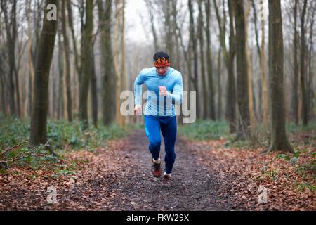 Vue avant pleine longueur de runner sur chemin bordé d'arbres à la bas Banque D'Images