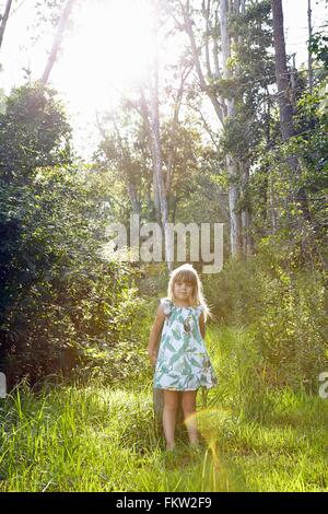 Girl standing against tree in forest Banque D'Images