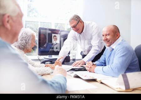 Les hommes d'affaires dans la fice avoir discussion avec senior couple Banque D'Images