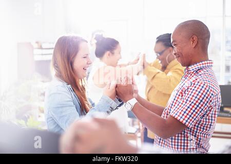 Vue latérale de collègues de travail d'équipe, face à face, mains ensemble smiling Banque D'Images