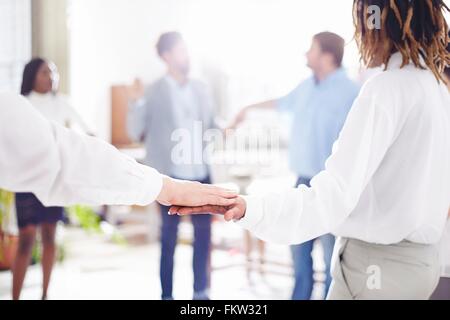 Collègues de travail team building standing in circle holding hands Banque D'Images