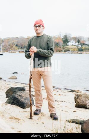 Portrait of mid adult man holding, bâton de marche, au bord du lac Banque D'Images