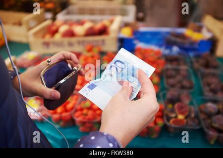 Jeune femme au marché, prendre de l'argent à partir de votre sac à main, mid section Banque D'Images