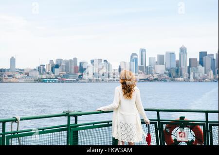 Vue arrière du woman looking at city skyline de traversier pour passagers sur le Puget Sound, Seattle, USA Banque D'Images