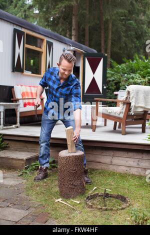 Mid adult man chopping logs du chalet Banque D'Images