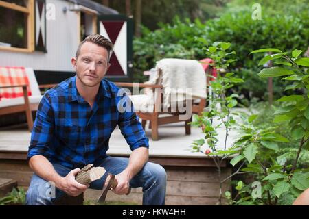 Portrait of mid adult man chopping logs du chalet Banque D'Images