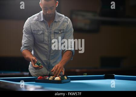 L'homme l'organisation des balles dans triangle sur table de billard Banque D'Images