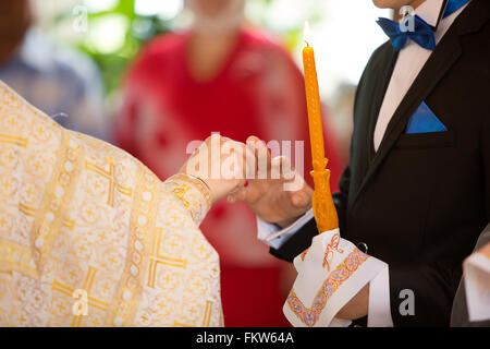 Le prêtre robes une bague sur un doigt pour le marié au cours de mariage à l'église Banque D'Images