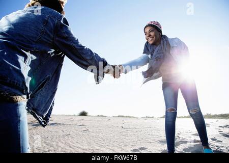 Deux amis de jouer au beach, holding hands, smiling Banque D'Images