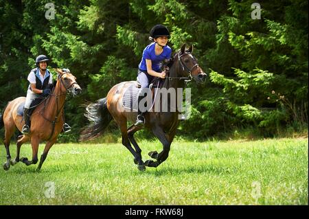 Femme mature et jeune fille à cheval au galop Banque D'Images