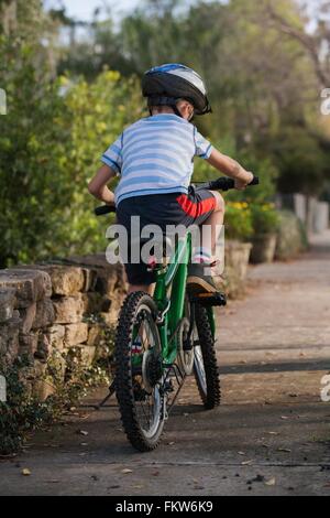 Boy riding bicycle sur le bas-côté de la route Banque D'Images