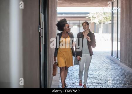 Deux jeunes femmes marchant et parlant à l'extérieur du bureau Banque D'Images