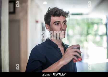 Jeune homme d'affaires graves de boire du café à emporter in office Banque D'Images