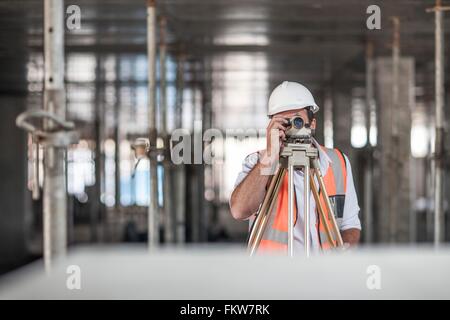 Mid adult male surveyor théodolite à on construction site Banque D'Images